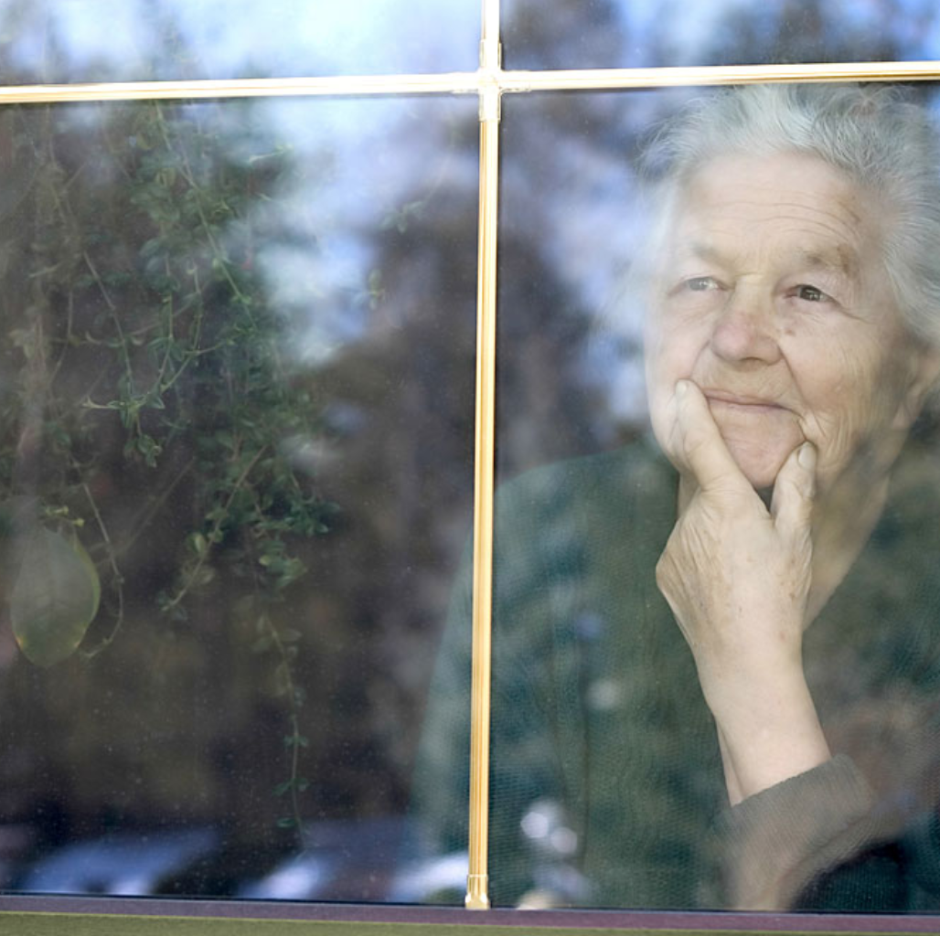 Eine ältere Frau schaut aus dem Fenster.