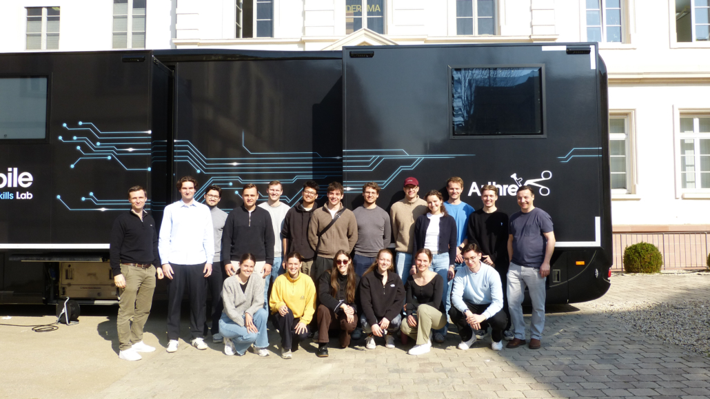 Medizinstudierende mit Prof. Dr. med. Becher (rechts im Bild) und PD Dr. med. Sowa (links im Bild) vor dem Arthrex-Truck mit Arthroskopie-Trainingsstationen.
